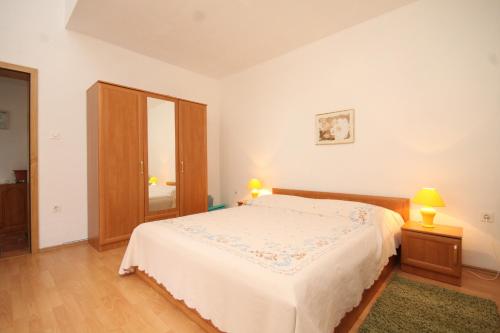 a white bedroom with a bed and two lamps at Apartments with a parking space Sveti Jakov, Losinj - 8011 in Nerezine