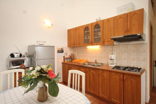uma cozinha com armários de madeira e uma mesa com um vaso de flores em Apartments with a parking space Sveti Jakov, Losinj - 8011 em Nerezine