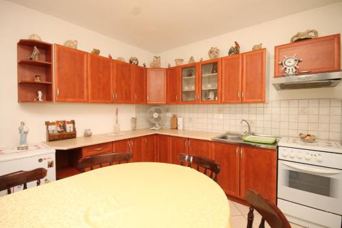 a kitchen with wooden cabinets and a table at Apartments with a parking space Cunski, Losinj - 8010 in Cunski