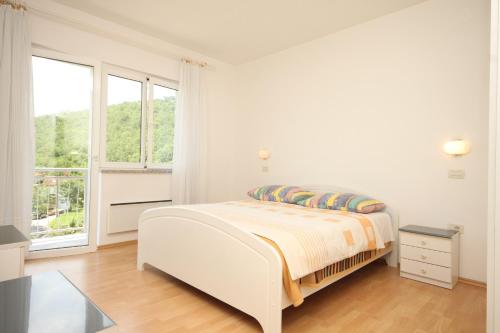 a white bedroom with a bed and a window at Apartments with a parking space Opatija - Pobri, Opatija - 7918 in Volosko