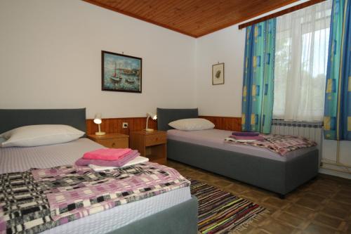 a bedroom with two beds and a window at Apartments and rooms by the sea Mali Losinj (Losinj) - 7953 in Mali Lošinj