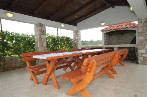 einen Picknicktisch und zwei Bänke auf einer Terrasse in der Unterkunft Apartments by the sea Pasman - 8215 in Pašman