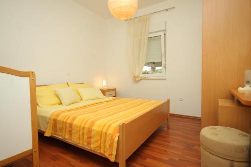 ein Schlafzimmer mit einem Bett mit gelber Bettwäsche und einem Fenster in der Unterkunft Apartments by the sea Pasman - 8215 in Pašman