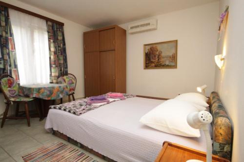 a small bedroom with a bed and a chair at Studio Mali Losinj 7953b in Mali Lošinj