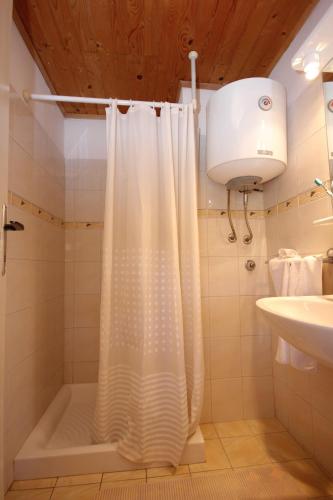 a bathroom with a shower with a white shower curtain at Apartments by the sea Zaglav, Dugi otok - 8191 in Sali