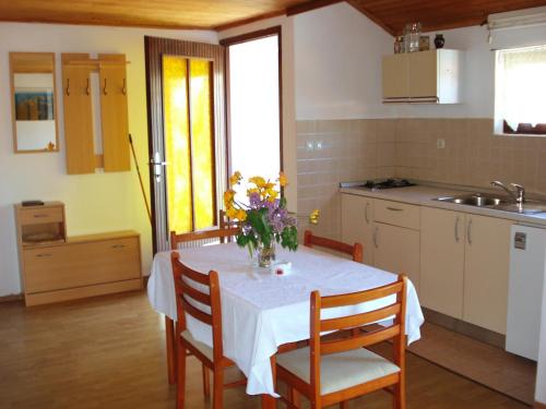 a kitchen with a table with a vase of flowers on it at Apartments by the sea Zaglav, Dugi otok - 8191 in Sali