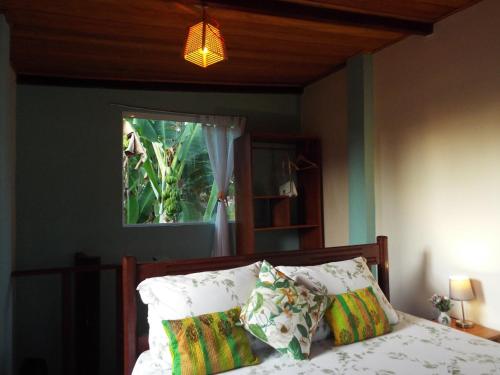 sypialnia z łóżkiem z poduszkami i oknem w obiekcie JARDIM UXUA w mieście Ilha de Boipeba