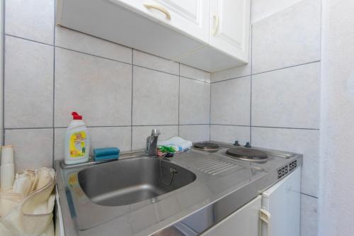 Il comprend une cuisine avec un évier et un mur carrelé blanc. dans l'établissement Apartment Podaca 6677d, à Podaca