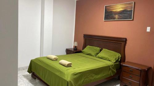 1 dormitorio con 1 cama verde y 2 toallas en Flavio Reyes en Manta