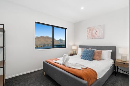 una camera da letto con un letto e una finestra di A Luckie Charm - 3-Bedroom Townhouse with Spectacular View a Queenstown