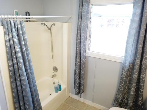 a bathroom with a tub and a shower curtain at Rainbow Ohana, unit 2 in Hilo