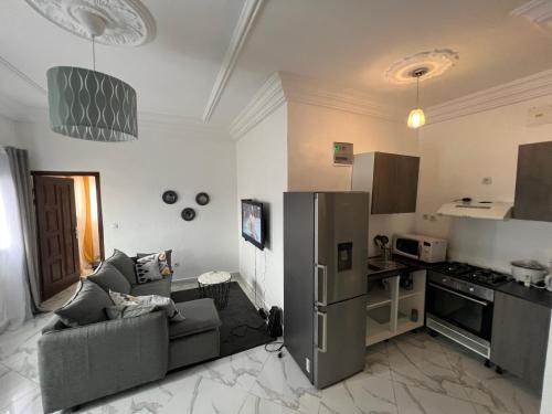 eine Küche und ein Wohnzimmer mit einem Sofa und einem Kühlschrank in der Unterkunft RÉSIDENCE MEUBLÉE 1ERE CLASSE DOUALA pk 15 in Douala