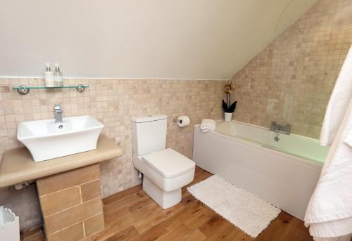 La salle de bains est pourvue d'un lavabo, de toilettes et d'une baignoire. dans l'établissement Moorland View Lodge, à Baslow