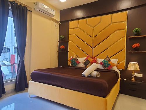 a bedroom with a large bed with a yellow headboard at OSI Apartments Lilavati Bandra in Mumbai