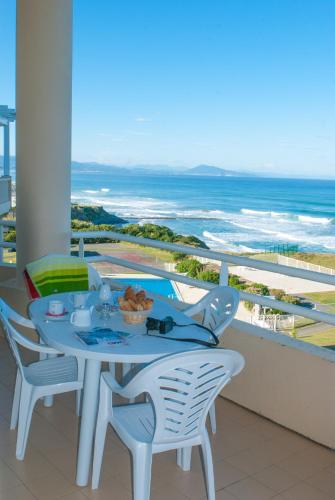 a table on a balcony with a view of the ocean at Résidence Mer & Golf Eugénie in Biarritz