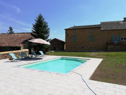 une piscine avec deux chaises et un parasol dans l'établissement Maison en pierre avec piscine privative, jardin, internet à Saint-Pardoux-et-Vielvic - FR-1-616-189, à Saint-Pardoux-et-Vielvic