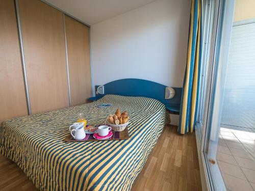 a bedroom with a bed with a tray of food on it at R&eacute;sidence Mer & Golf Eug&eacute;nie in Biarritz