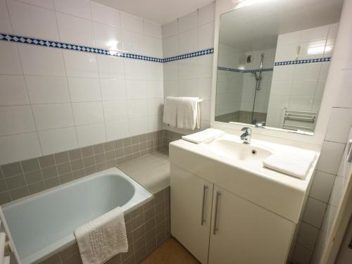 une salle de bain avec une baignoire, un lavabo et un miroir dans l'établissement Résidence Mer & Golf Eugénie, à Biarritz