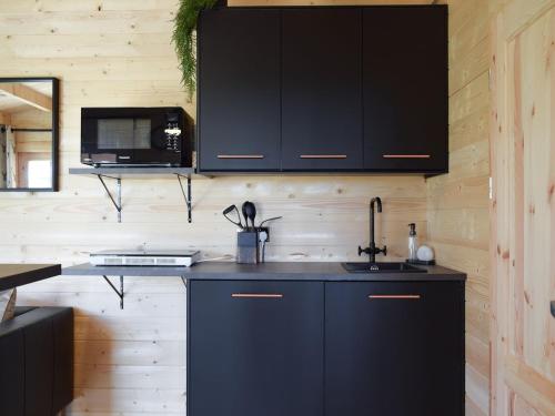 eine Küche mit schwarzen Schränken und einem Waschbecken in der Unterkunft Pinewood Cabin in Saline