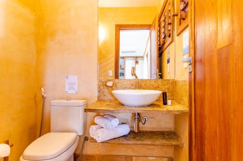 a bathroom with a sink and a toilet and a mirror at CasaLô Hotel in Jericoacoara