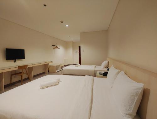a hotel room with two beds and a desk at Kaizen Suites in Manila