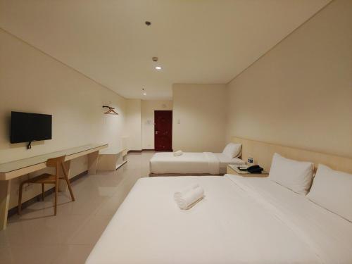 a hotel room with two beds and a desk at Kaizen Suites in Manila