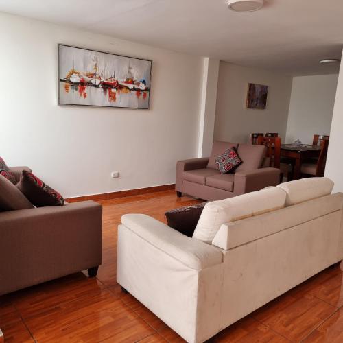 una sala de estar con 2 sofás blancos y una mesa. en Apart Hotel Cabral, en Lima