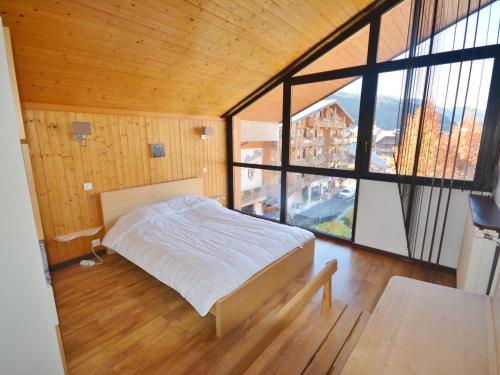 une chambre avec un lit et une grande fenêtre dans l'établissement **Duplex 6 pers. au centre de Morzine, proche pistes et remontées mécaniques** - FR-1-684-32, à Morzine