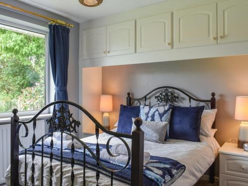 a bedroom with a bed with blue pillows and a window at Haweswater Cottage in Coundon