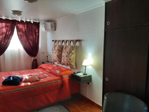1 dormitorio con cama roja y ventana en M & Mendoza en Mendoza