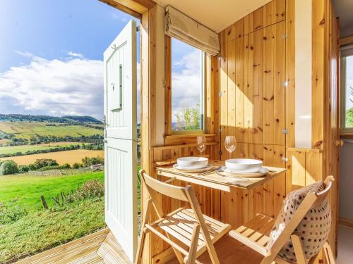 a dining room with a table and chairs and a window at Woodside Hut 2 - Uk36106 in Auchterneed