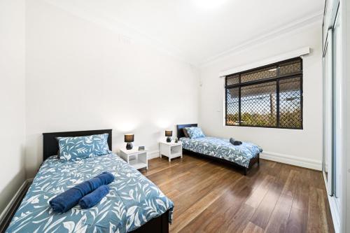 een slaapkamer met een bed, een bank en een raam bij 4 Bedroom house 500M to Drummoyne Bay Run in Sydney