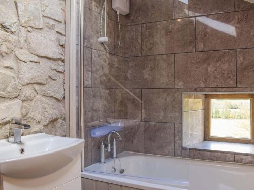a bathroom with a sink and a bath tub at Pentre Cwm Bach in Llansilin