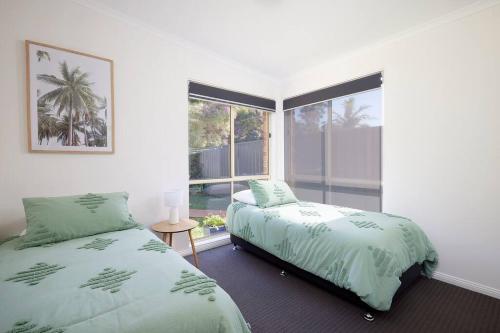 a bedroom with two beds and a window at The Atrium in Shoal Bay