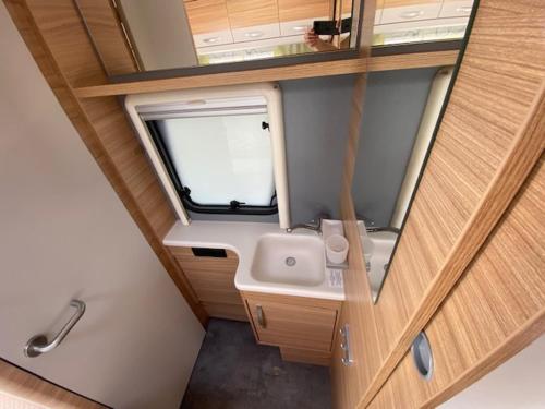 Elle comprend une petite salle de bains pourvue d'un lavabo et d'une fenêtre. dans l'établissement Wohnwagenvermietung CAMPING-SYLT / Morsum, à Westerwall