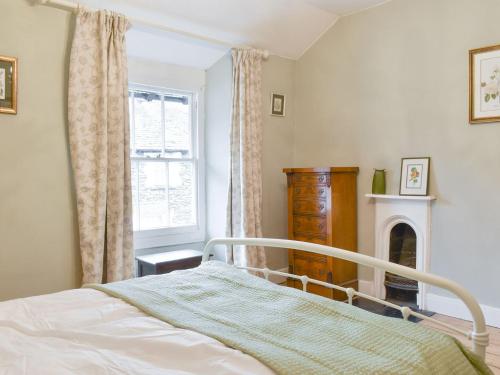 um quarto com uma cama, uma lareira e uma janela em Campbell Cottage em Windermere