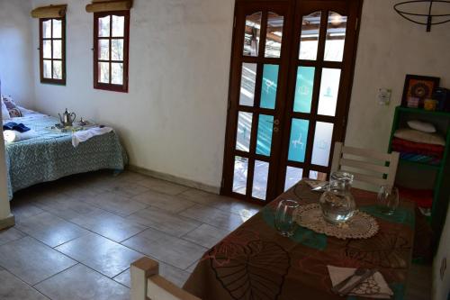 a room with a table and a bed with windows at Luz de Cabaña in Carpintería