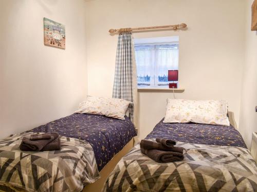 a bedroom with two beds and a window at Barn 2 in Ulverston