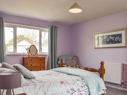 a bedroom with purple walls and a bed and a window at Furzy Cottage in Haverfordwest