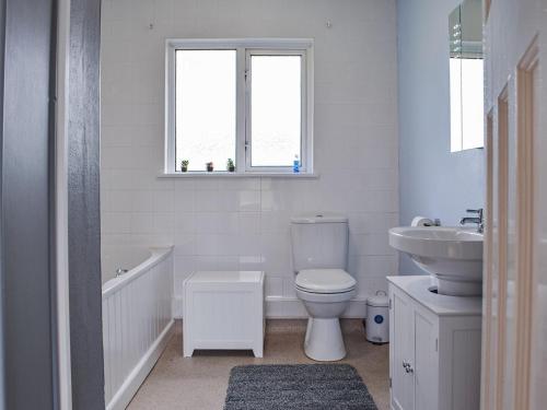 a white bathroom with a toilet and a sink at Furzy Cottage in Haverfordwest