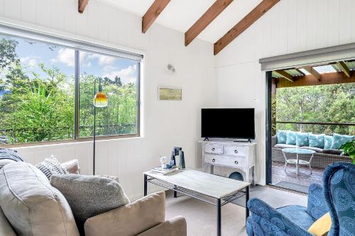 a living room with a couch and a tv at Refreshing Rainforest Retreat Kangaroo Valley in Kangaroo Valley