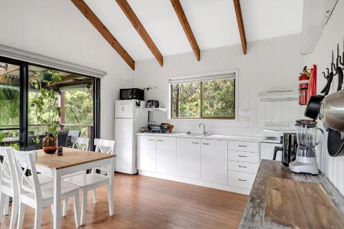 a kitchen with white appliances and a table and chairs at Refreshing Rainforest Retreat Kangaroo Valley in Kangaroo Valley
