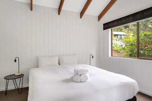 1 dormitorio con 1 cama blanca y 2 toallas en Refreshing Rainforest Retreat Kangaroo Valley, en Valle Kangaroo