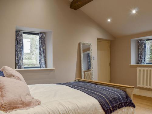 a bedroom with a bed with a mirror and windows at The Old Shippon At New Ringstones Farm in Mellor