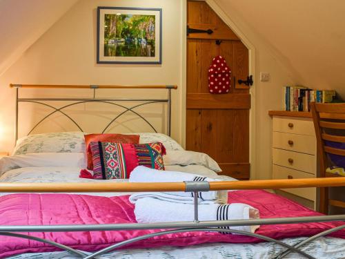 a bedroom with a bed with pink sheets and a wooden frame at Loftings in Hendred