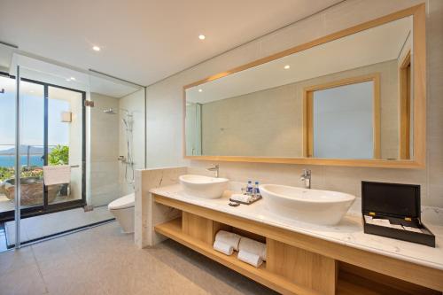 a bathroom with two sinks and a large mirror at Da Nang - Mikazuki Japanese Resorts & Spa in Da Nang
