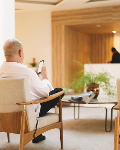 a man sitting in a chair reading a book at Blue Tree Premium São Luis in São Luís