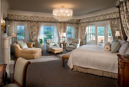 a bedroom with a bed and chairs and a chandelier at The Broadmoor in Colorado Springs