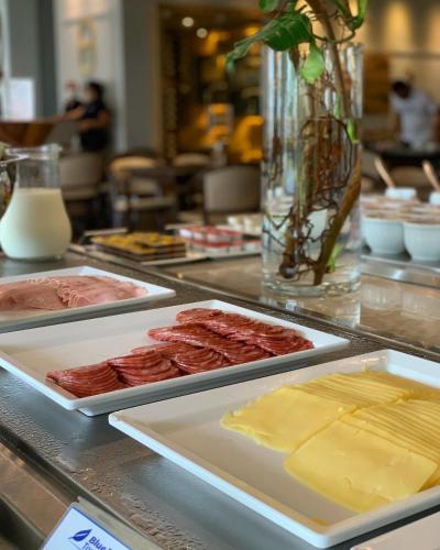 a counter with several plates of meats and cheese at Blue Tree Premium São Luis in São Luís