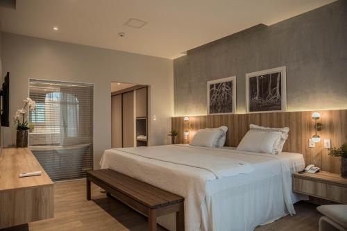 um quarto com uma grande cama branca e um banco em Blue Tree Towers São Luis em São Luís